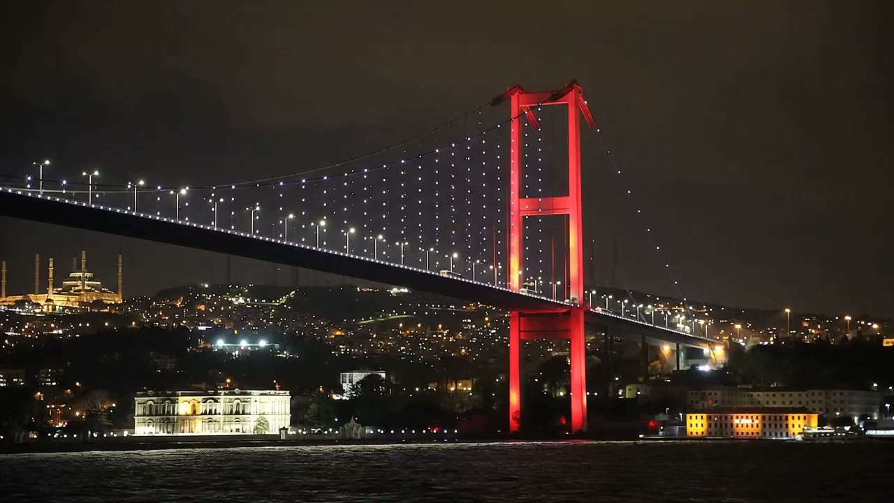 Bosphorus Bridge lit red at night above the Istanbul shoreline