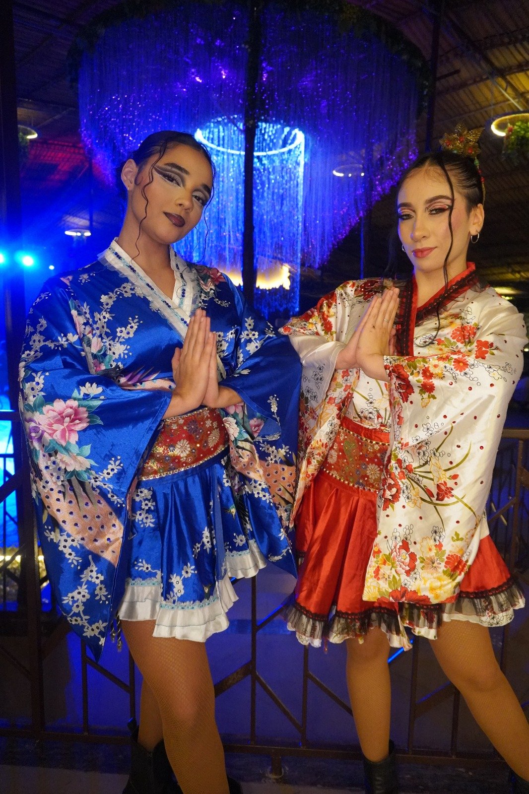 Two performers in blue and white kimono-inspired costumes under a crystal chandelier